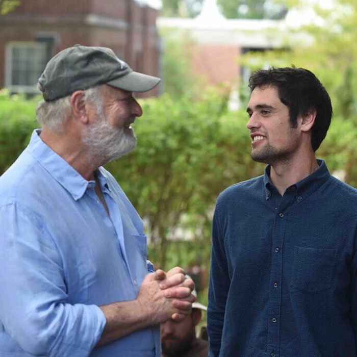 Two men smiling and talking outdoors, captured in a candid moment about Michelle Obama and Trump news. Two men smiling and talking outdoors, captured in a candid moment about Michelle Obama and Trump news.