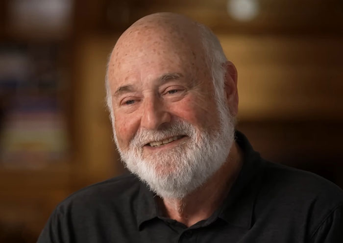 Elderly man with white beard smiling warmly in a wood-paneled room, related to person of interest after grisly LA home incident Elderly man with white beard smiling warmly in a wood-paneled room, related to person of interest after grisly LA home incident