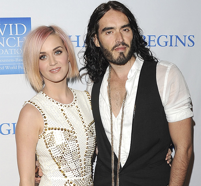 Russell Brand and Katy Perry posing together at a public event, capturing their past relationship dynamic.