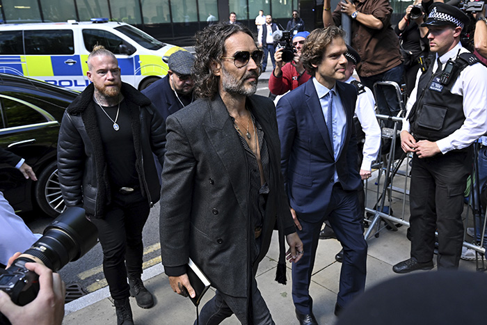 Russell Brand wearing sunglasses, walking past police and media, reacting to ex-wife Katy Perry&rsquo;s new relationship with Justin Trudeau.