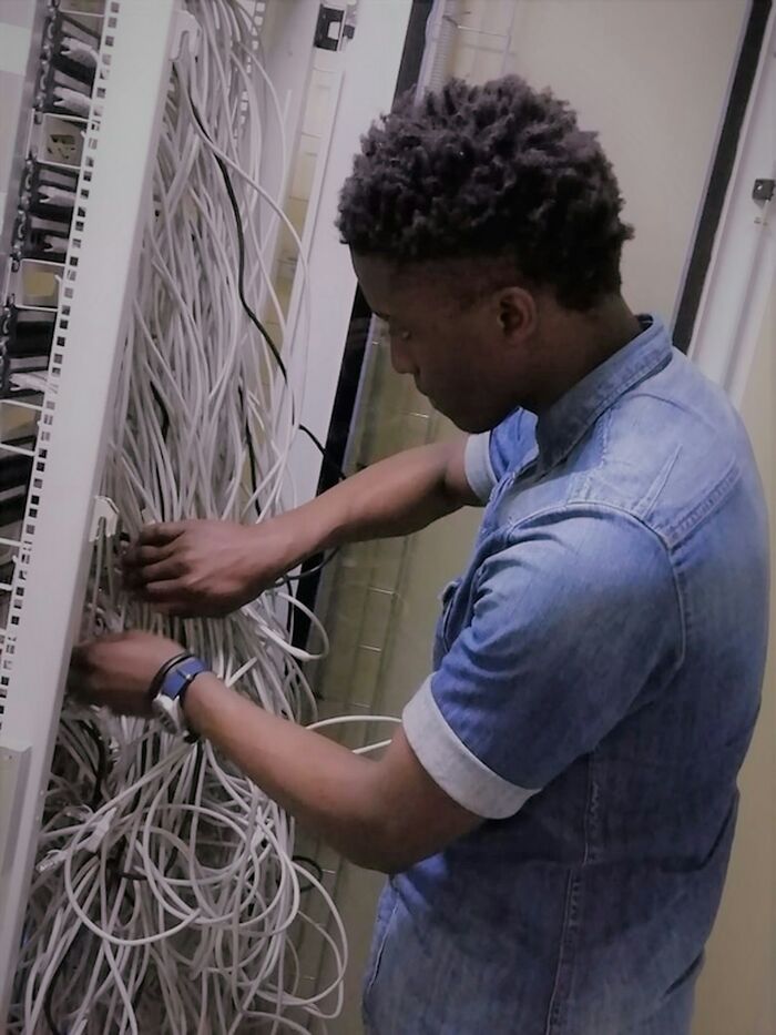 Man working with tangled network cables in a server room, illustrating infuriating moments people experienced while working.
