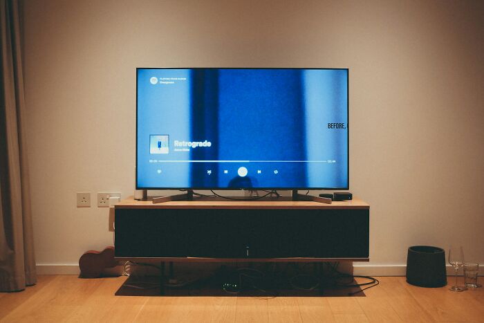 TV screen displaying a music player in a minimal living room, illustrating secrets people trust strangers online with.