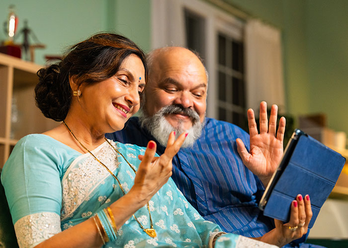 Middle-aged parents using a tablet, smiling and waving during a video call, depicting a family held hostage scenario. Middle-aged parents using a tablet, smiling and waving during a video call, depicting a family held hostage scenario.