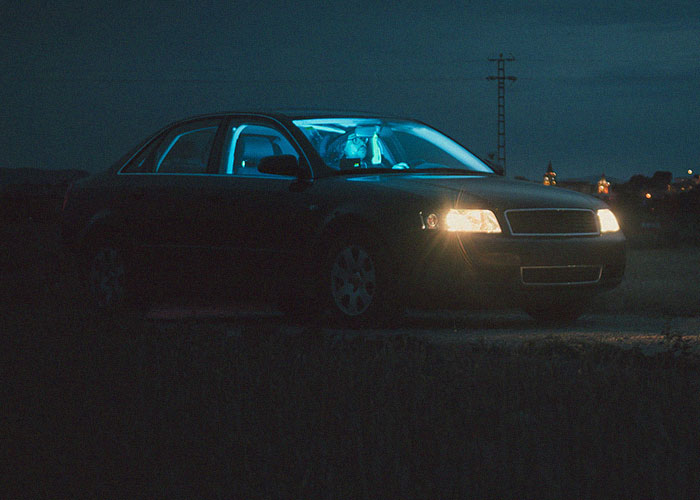 Person inside a dark car at night, appearing distressed and held hostage at their parents’ place, unsure of what to do. Person inside a dark car at night, appearing distressed and held hostage at their parents’ place, unsure of what to do.