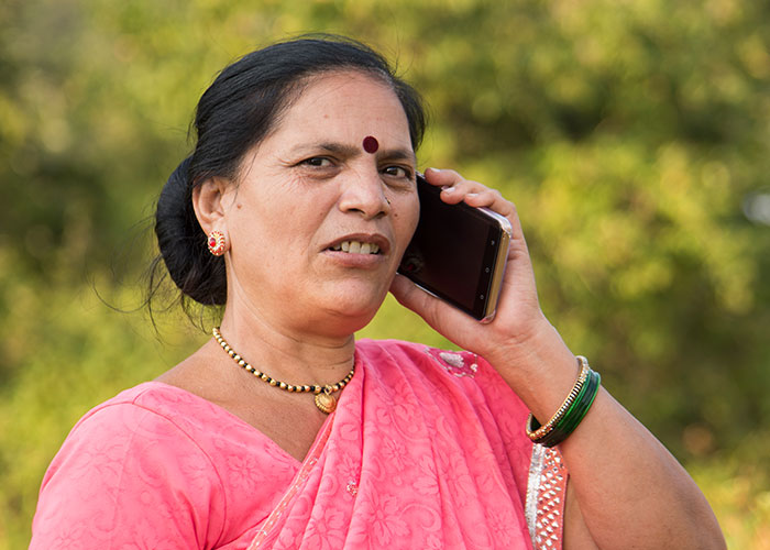 Woman in pink sari holding phone, appearing concerned, illustrating being held hostage at parents’ place situation. Woman in pink sari holding phone, appearing concerned, illustrating being held hostage at parents’ place situation.