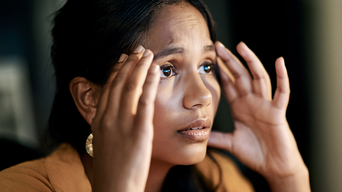 Worried woman holding her head in stress, reflecting feelings of being held hostage at parentsu2019 place and uncertainty.