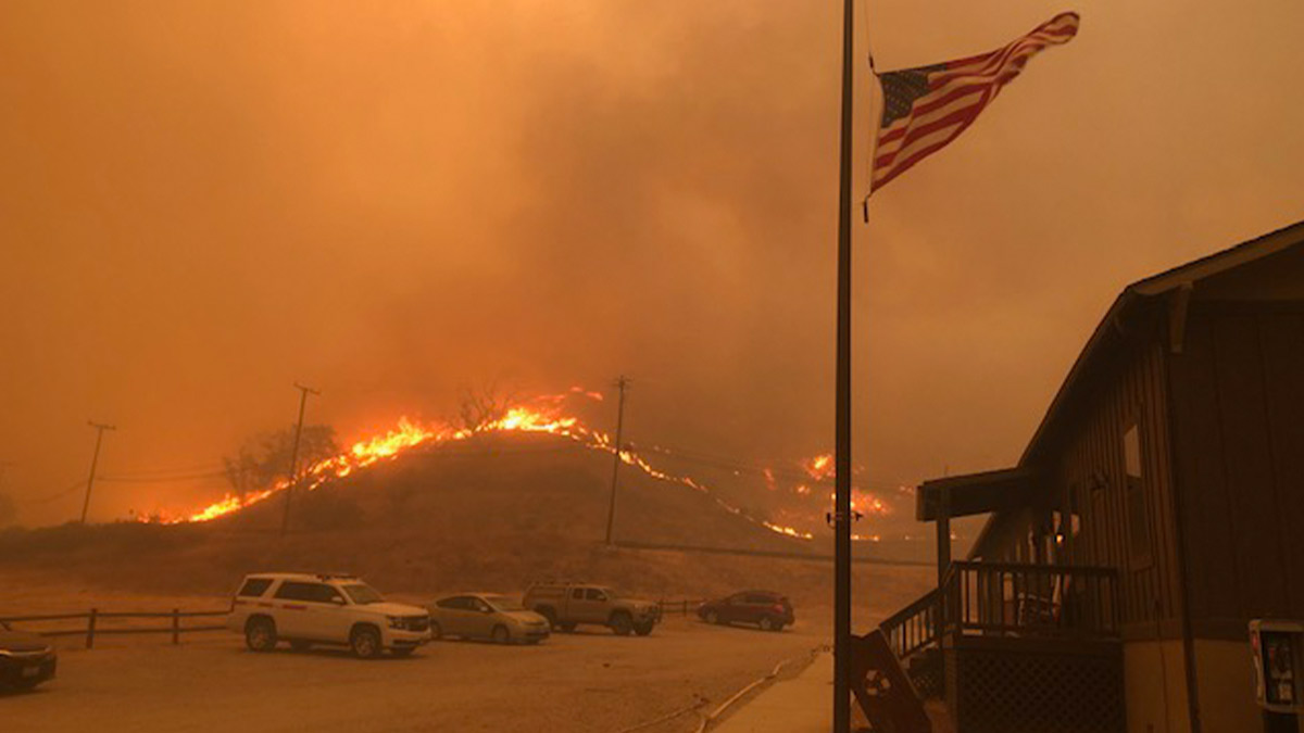 Wildfire blazing on hillside near homes and vehicles as people instinctively knew something was wrong and left quickly