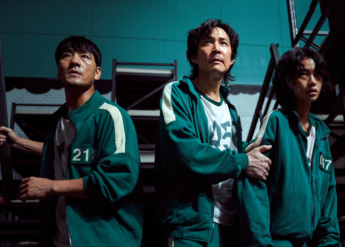 Three people in green tracksuits with numbers, portraying characters related to Squid Game prank investigation. Three people in green tracksuits with numbers, portraying characters related to Squid Game prank investigation.