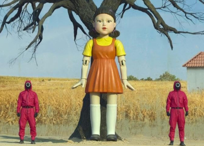 Giant doll from Squid Game show standing by tree with two guards, related to schoolboy incident investigation details. Giant doll from Squid Game show standing by tree with two guards, related to schoolboy incident investigation details.
