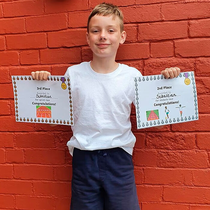 Schoolboy holding certificates against red brick wall, related to investigation of squid game prank incident. Schoolboy holding certificates against red brick wall, related to investigation of squid game prank incident.
