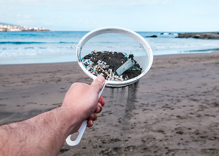Hand holding sieve with microplastics collected from beach sand, highlighting microplastics contamination in natural environments. Hand holding sieve with microplastics collected from beach sand, highlighting microplastics contamination in natural environments.