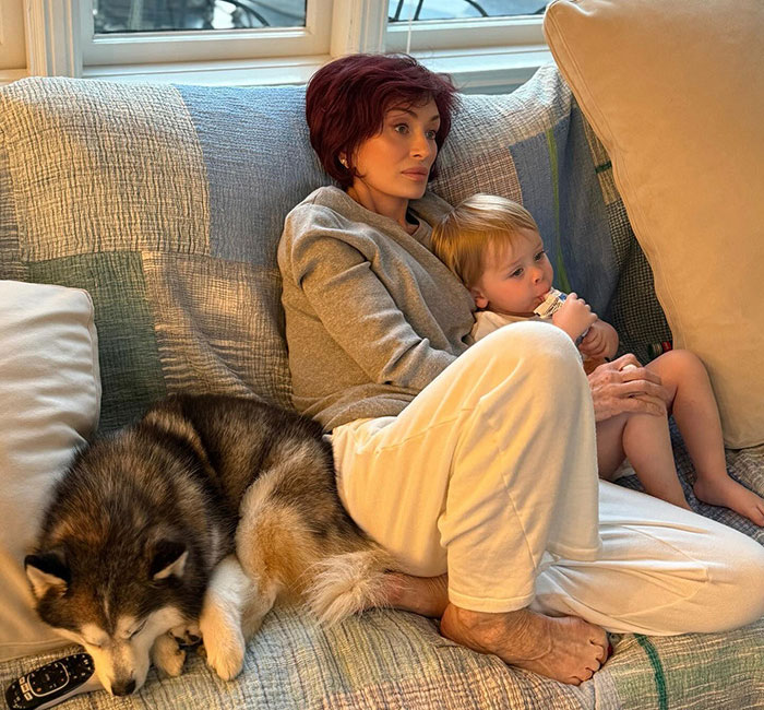 Kris Jenner sitting on a couch with a child and dog, showing hands without gloves after viral facelift news. Kris Jenner sitting on a couch with a child and dog, showing hands without gloves after viral facelift news.