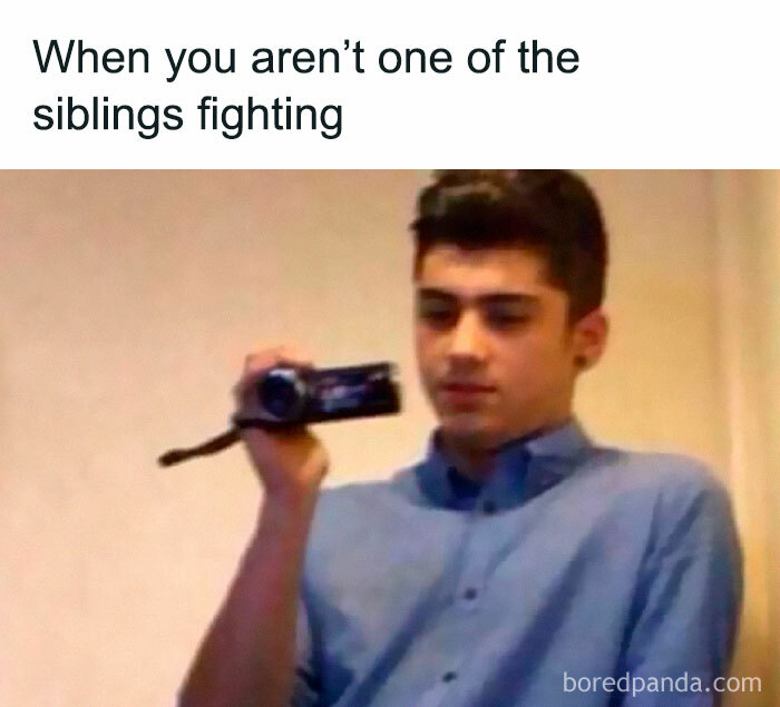 Teenager calmly recording on a camcorder, illustrating sibling memes about what it means to have siblings.