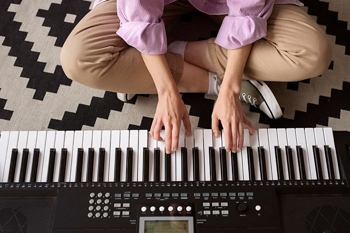 Person sitting cross-legged on a rug playing a keyboard, illustrating a man&rsquo;s promise to contribute $400 per kid for Christmas.