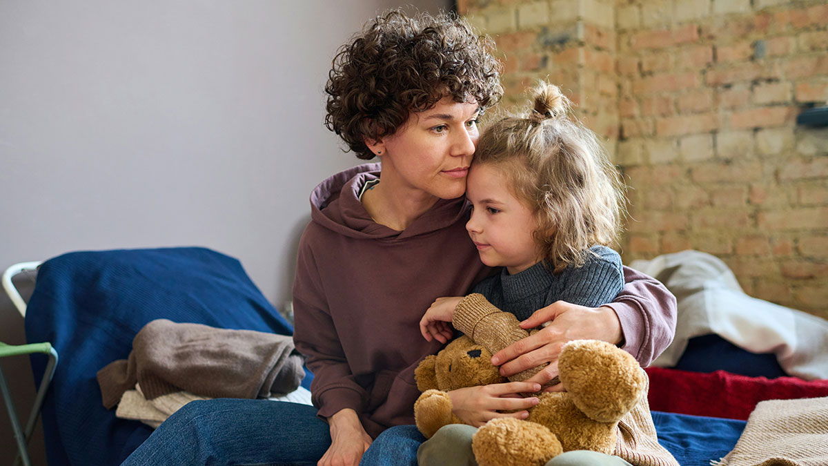 Woman comforting her child holding a teddy bear, reflecting emotions related to autistic son and CPS call.