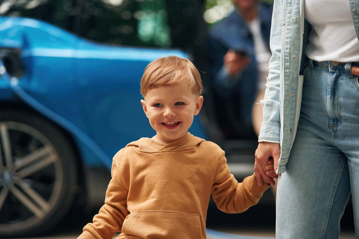 Young boy with autism holding his mother's hand outdoors, highlighting a family situation involving CPS and empathy concerns.
