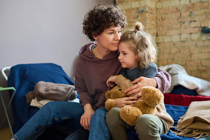 Mother comforting her autistic son holding a teddy bear, upset after sister called CPS for an empathy lesson. Mother comforting her autistic son holding a teddy bear, upset after sister called CPS for an empathy lesson.