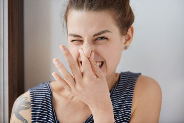Young woman laughing and covering her nose, showing amusement at entitled boys will be boys behavior in family conflict context. Young woman laughing and covering her nose, showing amusement at entitled boys will be boys behavior in family conflict context.