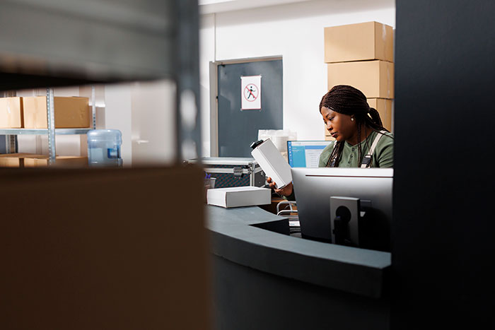 Woman working in a warehouse inspecting a package, illustrating clever tactics used by wiliest criminals to outsmart police officers.