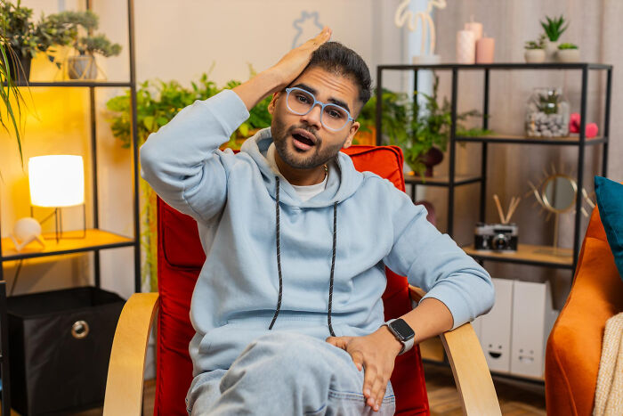 Man in glasses and hoodie looking surprised while sitting in a red chair, relating to most likely to succeed stories.