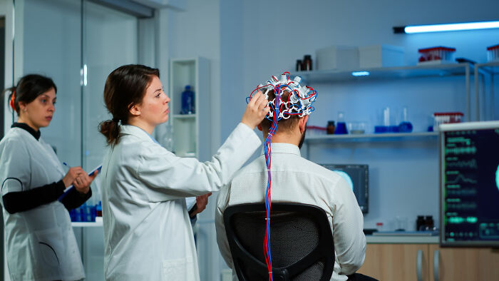 Scientist testing brain activity on a man using EEG equipment, exploring success and plot twists in a research setting.