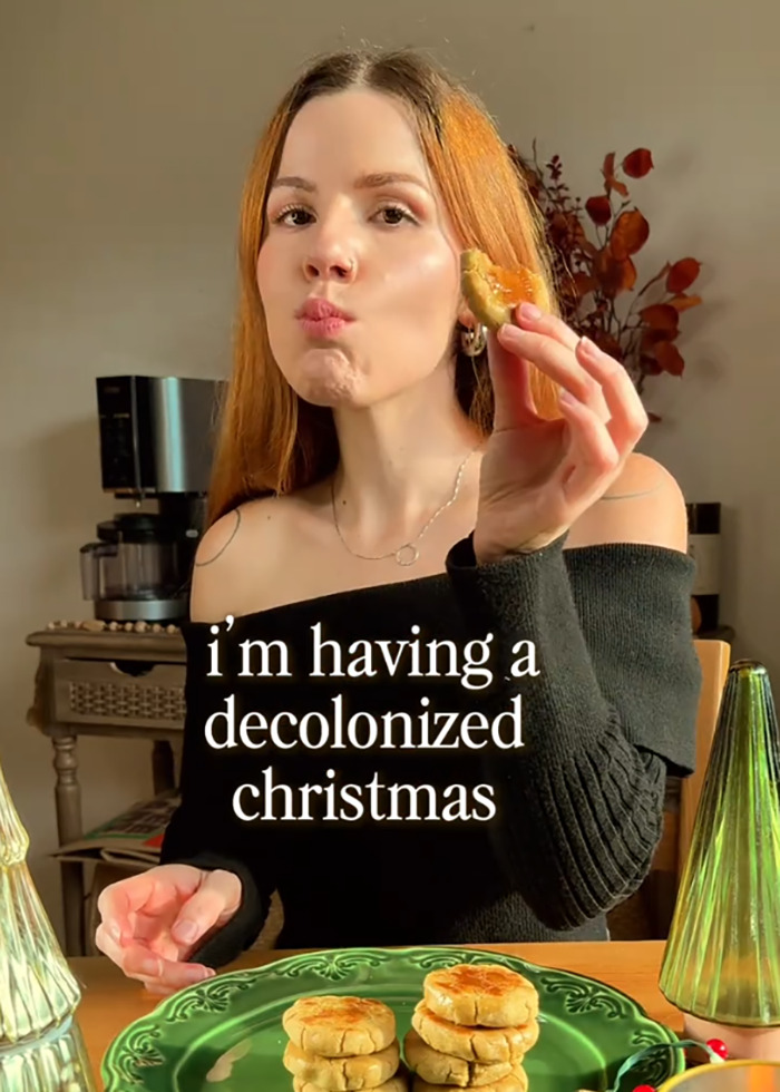 Young social media user eating cookies at table with festive decor, referencing decolonized Christmas trend. Young social media user eating cookies at table with festive decor, referencing decolonized Christmas trend.
