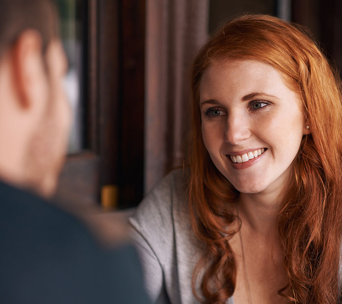 Woman smiling and engaging in conversation, illustrating psychological cheat codes for easier social life interactions.