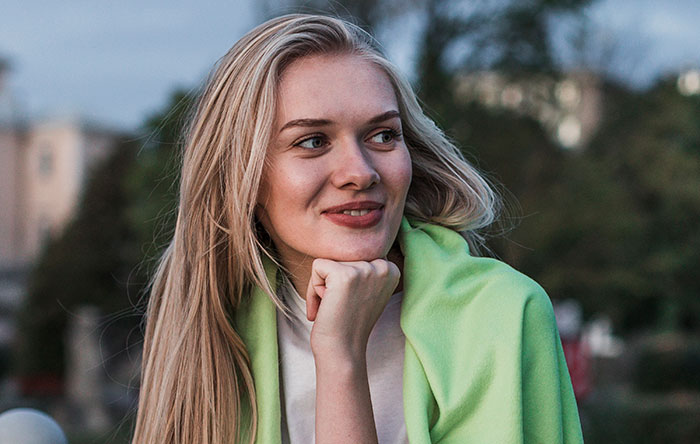 Young woman looking thoughtfully with a green jacket outdoors, illustrating psychological cheat codes for easier social life.