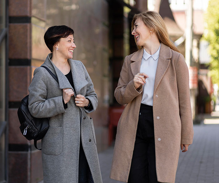 Two women smiling and talking outdoors, demonstrating psychological cheat codes for easier social life interaction.