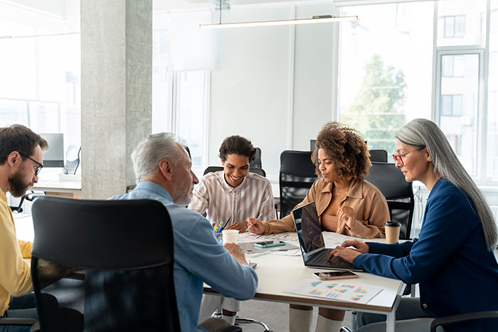 A diverse group of professionals using psychological cheat codes in social situations during a collaborative office meeting.