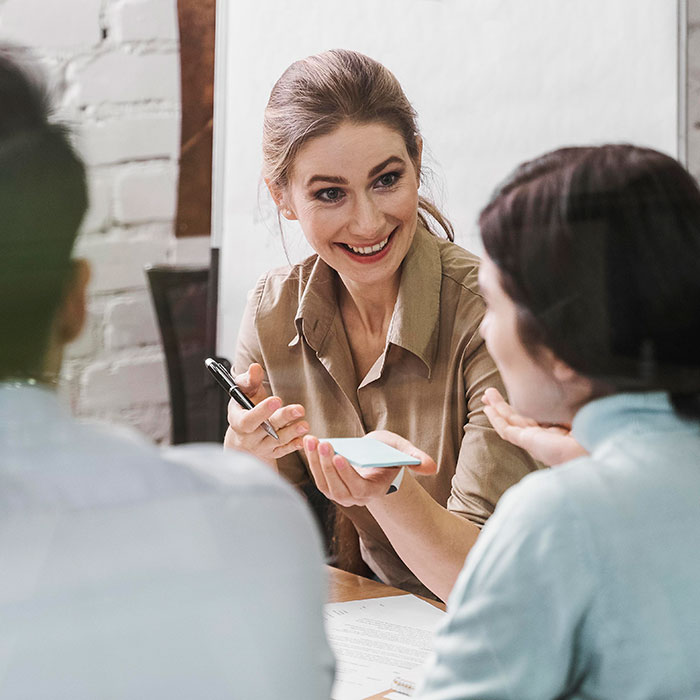 Smiling woman using psychological cheat codes while interacting with two people in a casual social setting.