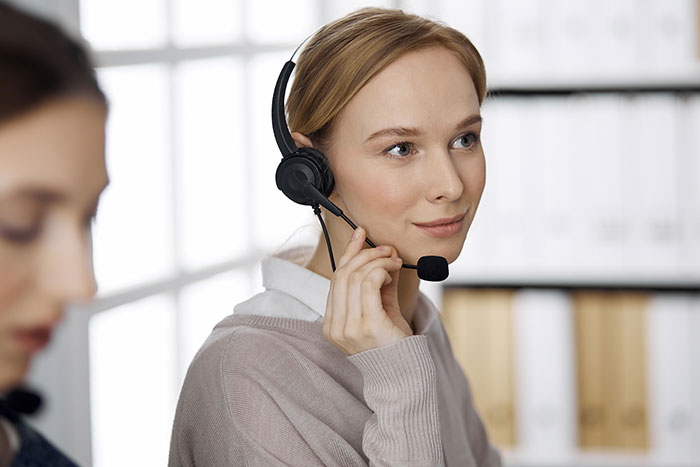 Young woman wearing a headset using psychological cheat codes to improve social life in a modern office setting.