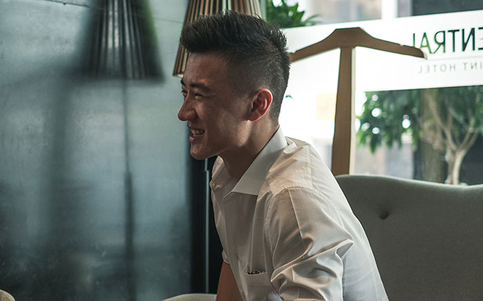 Young man smiling and engaging in conversation indoors, illustrating psychological cheat codes that improve social life.