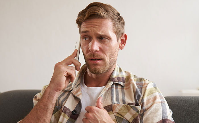 Man in a plaid shirt using psychological cheat codes during a phone call to improve social life and communication skills.