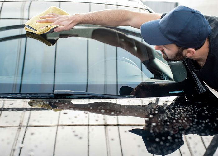 Man cleaning car windshield with cloth, illustrating diabolical revenge stories and acts of retaliation.