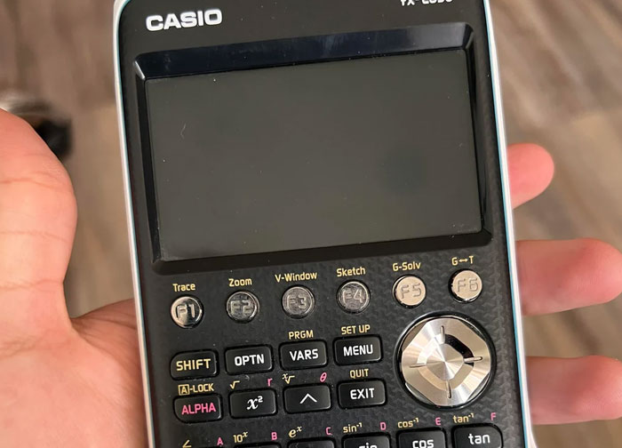 Hand holding a Casio scientific calculator, illustrating precise calculations for diabolical revenge stories and enemies.