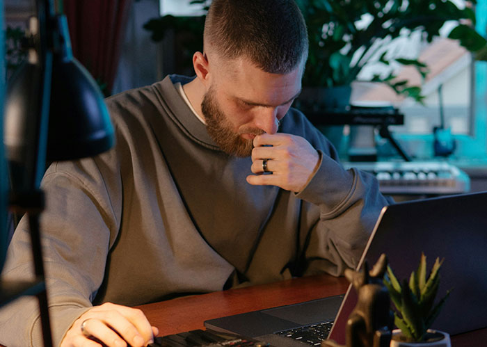 A thoughtful man working late on a laptop, representing intense focus on diabolical revenge stories online.