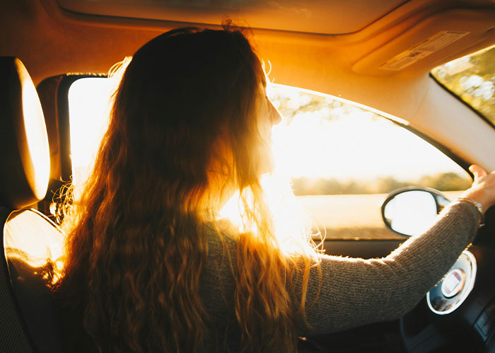 Woman with long hair driving a car at sunset, illustrating diabolical revenge stories from people you wouldn't want as enemies.
