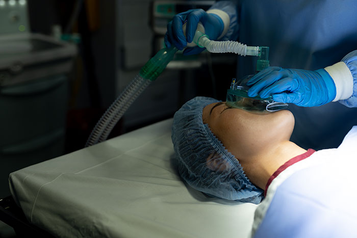Patient receiving anesthesia with oxygen mask in a hospital setting, capturing the panic and seriousness on his face.