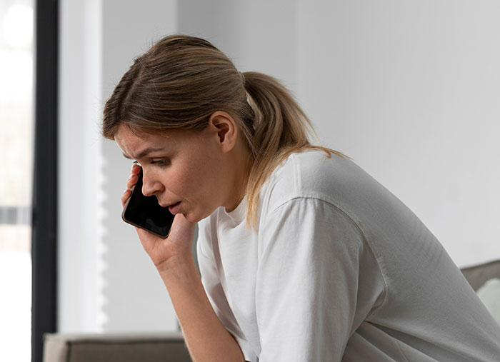 Woman with panic on his face talking on phone, showing a serious moment despite skepticism around her.