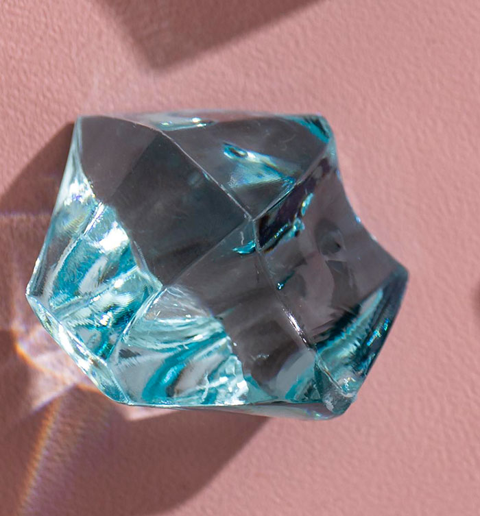 Close-up of a shiny transparent crystal with reflections and shadows, highlighting the panic on his face concept.