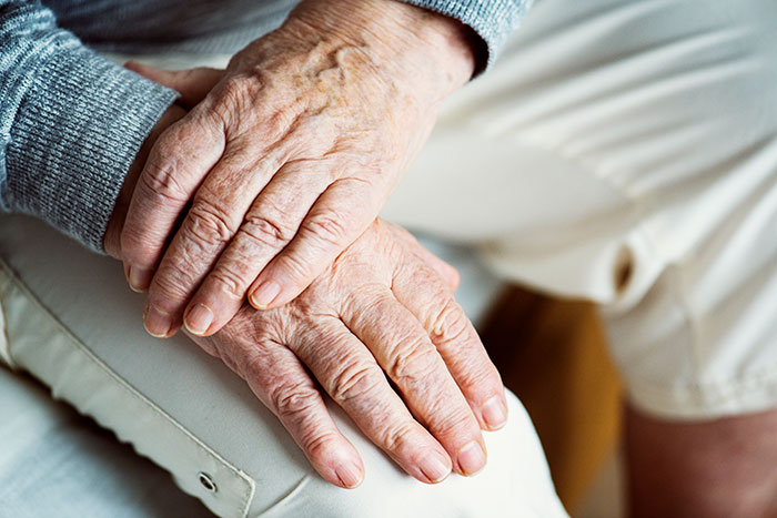 Close-up of elderly hands resting on a knee, illustrating things people never took seriously until experienced themselves.