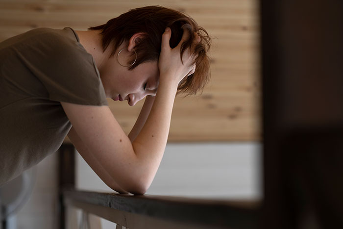 Young woman holding her head in hands, experiencing stress and reflection, illustrating things people believe once it happens to them.