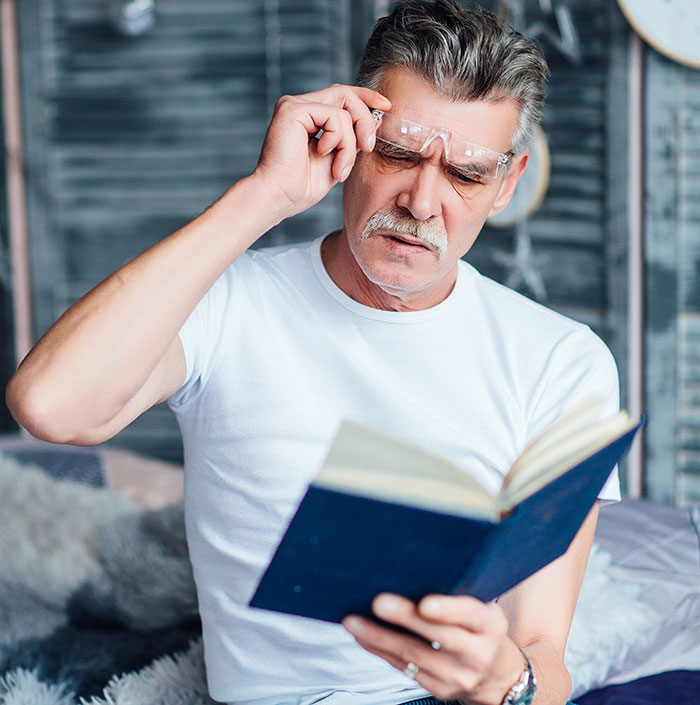 Man wearing glasses and reading a book closely, sharing things people only started to believe once experienced.