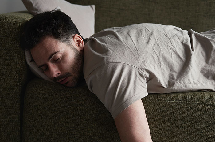 Man lying face down on a couch, showing exhaustion, illustrating experiences people only believed once it happened to them.