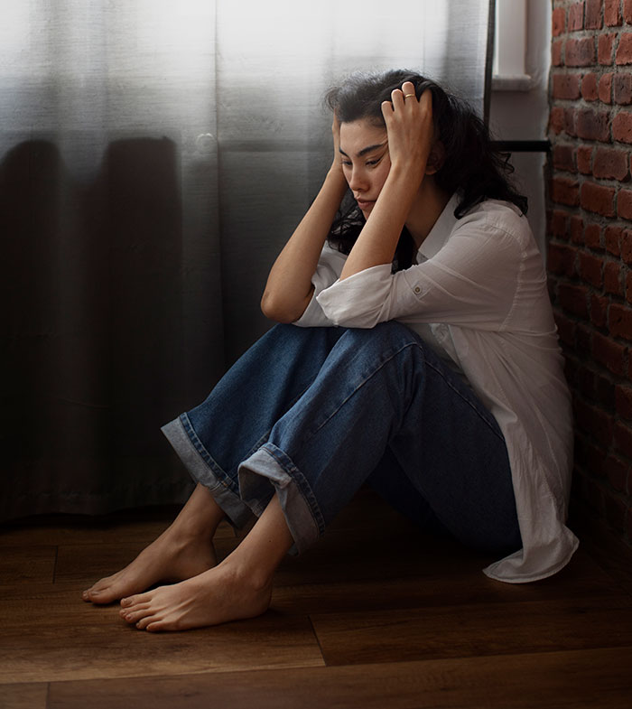 Woman sitting on floor with head in hands, reflecting on experiences people only believe once it happened to them.