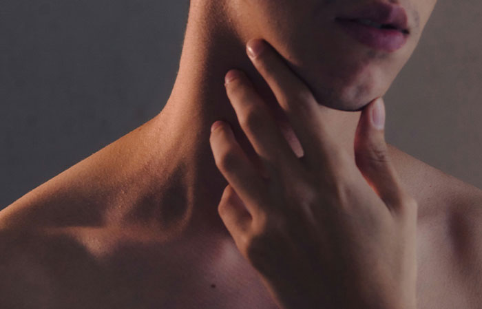 Close-up of a person touching their neck, highlighting human body features related to the mammalian dive reflex.