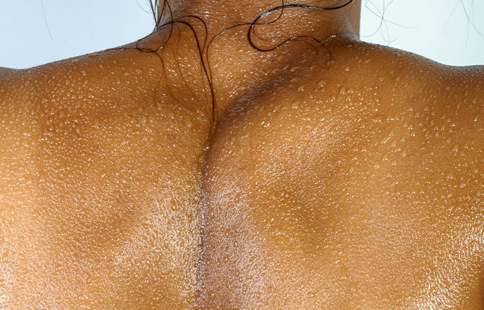 Close-up of a wet human back showing skin texture and water droplets, illustrating the mammalian dive reflex in the human body.