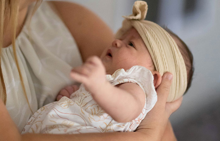 Mother holding infant wearing headband, illustrating the human body and mammalian dive reflex concept.