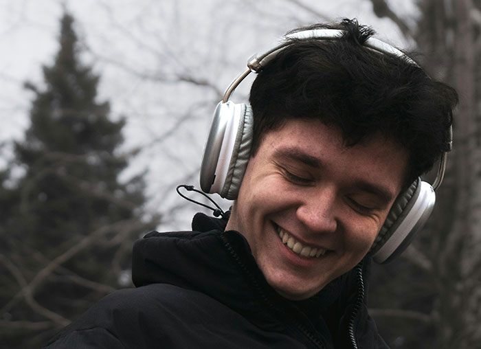 Young man smiling outdoors with headphones, illustrating concepts related to the mammalian dive reflex in the human body.